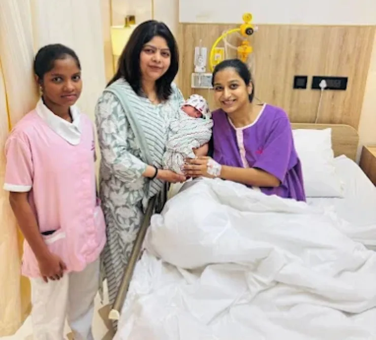 Dr. Bhavya Rathore in surgical scrubs holding a newborn after delivery